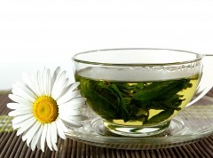прозрачная чашка зелёного чая с травами и ромашкой