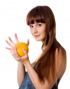 девушка держит в руках апельсин