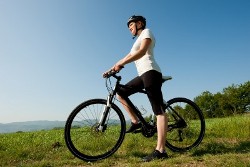молодая женщина на велосипеде на фоне красивой природы