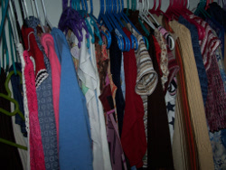 много женской одежды на вешалках в шкафу