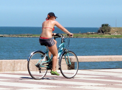 девушка в шортах едет на велосипеде вдоль моря